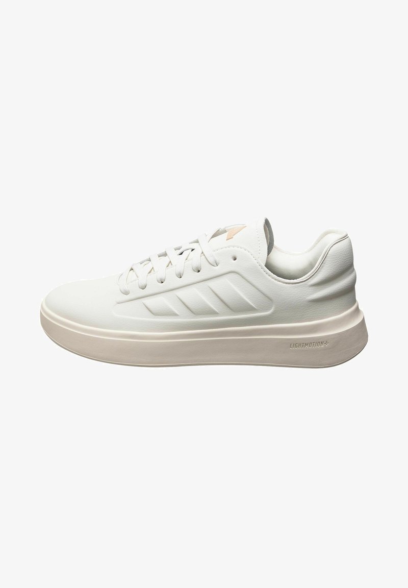 Sneaker atletico bianco con una superficie liscia, design con lacci e una suola leggermente rialzata. Presenta tre strisce diagonali su un lato.