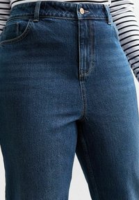 Niebieskie dżinsy z wysokim stanem, pięcioma kieszeniami, zapięciem na metalowy guzik oraz kontrastowym przeszyciem. Gładka faktura i klasyczny, prosty krój.