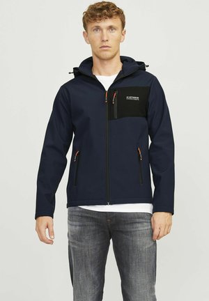 Chaqueta softshell azul marino con un bolsillo en el pecho negro, cremalleras naranjas, capucha y dos bolsillos laterales; tela texturizada con un diseño minimalista.