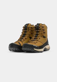 Rudos žygių batai su orui laidžiu viršumi, juodu guminiu padu, tekstūruotais raišteliais ir sustiprinta piršto sritimi. Ant šono matomas prekės ženklas.