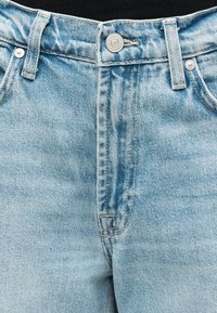 Ζώνη από ανοιχτό μπλε τζιν με κούμπωμα με κουμπί, θηλιές για ζώνη και ορατές μπροστινές τσέπες σε μαύρο φόντο.