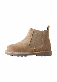 Botte ankle en daim marron avec panneaux latéraux élastiques, bout arrondi et semelle en caoutchouc. Dispose d'une languette pour un enfilage facile.
