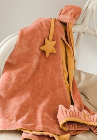 Blødt koralfarvet fløjlstøj med gule accenter, stjerneformet detalje og ribbet kant. Indeholder små ufuldkommenheder og et hyggeligt design.
