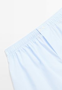 Boxers en coton bleu clair avec un motif rayé subtil, featuring une taille élastique et deux boutons à l'avant.