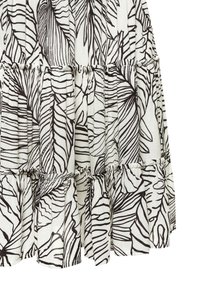 Gonna a strati realizzata in tessuto leggero, con uno sfondo bianco caratterizzato da audaci motivi a foglia nera e delicate righe testurizzate.