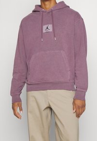 Felpa con cappuccio in un viola tenue, dotata di tasca frontale, cappuccio con lacci e una toppa grafica centrata. Realizzata in morbido misto cotone.