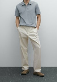 Grå polo t-shirt, cremefarvede bukser, mørkebrune slip-on sko. Glat stof, klassisk krave, afslappet pasform og minimalistisk design.