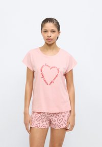 Ροζ τοπ με κοντά μανίκια και κείμενο «love» σε σχήμα καρδιάς και αντίστοιχα σορτς με κόκκινα σχέδια καρδι ών, κατασκευασμένα από απαλό ύφασμα.