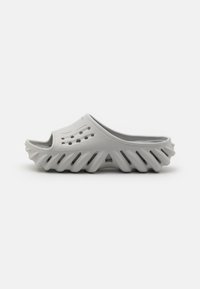 Grå formgjuten slid sandal med öppen tå, texturerad överdel och vågiga sidor, med ventilationshål längs toppen för andningsförmåga.