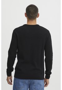 Black knitted sweater with long sleeves, round neck, and ribbed cuffs and hem. Smooth texture, no visible patterns or hardware details.