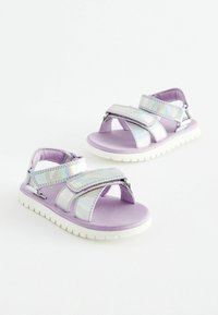 Lila sandaler med iriserande remmar, justerbara kardborrestängningar och en texturerad vit gummisula för bra grepp och komfort.