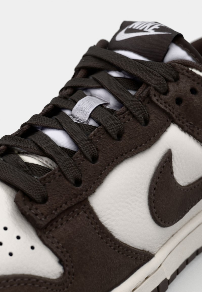 Sneaker in pelle marrone e crema con lacci scuri, presenta una linguetta imbottita, punta perforata e il logo swoosh sul lato.