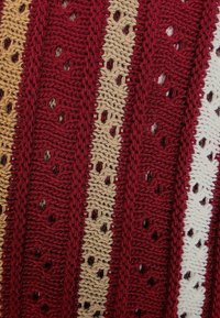 Dzianina o wzorze naprzemiennych pasów w ciemnoczerwonym, beżowym i białym kolorze, z teksturowanym wzorem i małymi ażurowymi otworami.