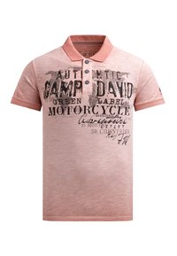 Heren polo shirt van zacht roze stof. Beschikt over een kraag en een knoopsluiting met drie knopen. De voorkant heeft zwarte tekst en grafische afbeeldingen met een wereldkaartpatroon.
