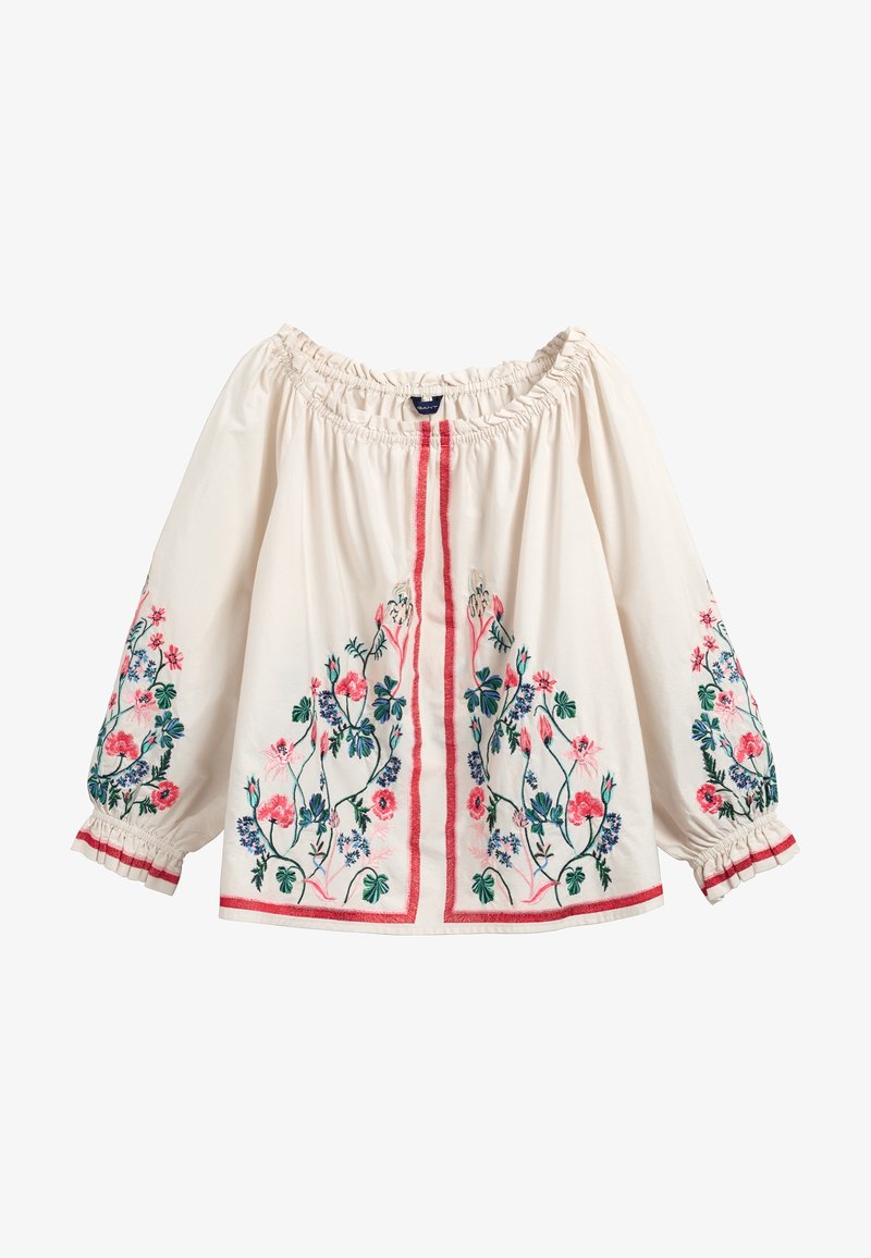 Blouse écrue épaules dénudées avec encolure et poignets élastiqués, broderie florale rose, verte et bleue sur le devant et les manches avec bordure rouge.