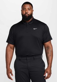 Czarna koszulka polo Nike z trzema guzikami i białym logo na lewej piersi, w zestawie z czarnymi spodniami. Gładki, oddychający materiał.