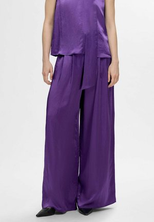 Top in satin viola con design drappeggiato, abbinato a pantaloni larghi in satin viola. Entrambi hanno una consistenza liscia e uno stile minimalista.