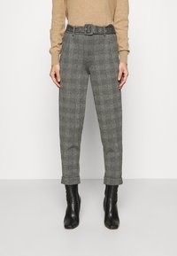Pantaloni a quadri grigi con vita con cintura, fronte plissettato, polsini cropped e vestibilità su misura, abbinati a stivaletti neri.