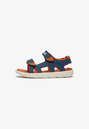 Sininen ja oranssi sandaal, jossa on säädettävät Velcro-nauhat, avoimet leikkaukset ja teksturoitu sisäpohja, jossa on valkoinen kumipohja.