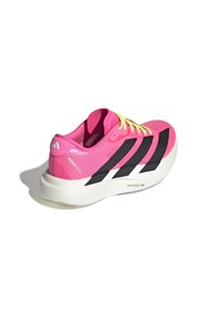 Pink athletic shoe with black stripes, textured mesh upper, and bright yellow laces. Features a white midsole labeled "LIGHTSTRIKE PRO."