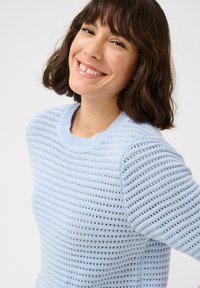 Pull en tricot bleu clair avec un motif en tissage ouvert texturé et un col rond. Les manches sont de coupe décontractée, mettant en avant un design respirant.