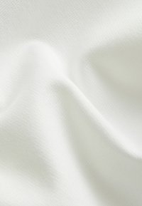 Weißer, strukturierter Stoff mit einem dezenten gerippten Muster, der weich und drapiert wirkt. Die Oberfläche zeigt sanfte Wellen und Falten.