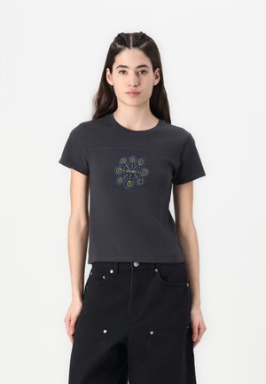 Sort bomulds t-shirt med korte ærmer, prydet med en farverig svulm brodering i midten, kombineret med sorte højtaljede bukser.