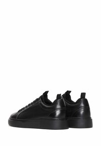 Sneaker in pelle nera con superficie liscia, punta rotonda, suola in gomma piatta e lacci neri. Presenta linguette posteriori per una facile calzata.
