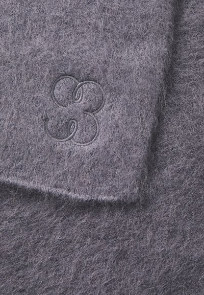 Pilkas vilnos gaminys su lygia tekstūra ir iškiliais siuvinėjimo gėlės motyvais. Forma – stačiakampė su švelniais kraštais.