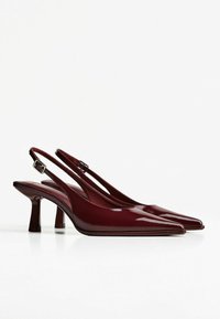 Pantofi cu toc slingback din piele lăcuită burgundă, cu vârf ascuțit și toc subțire, pe un fundal alb.