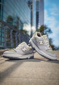 Baskets gris et vert clair avec une tige en suède et maille, dotées d'une semelle épaisse et d'un logo 'N' sur le côté. Lacets et col rembourré inclus.