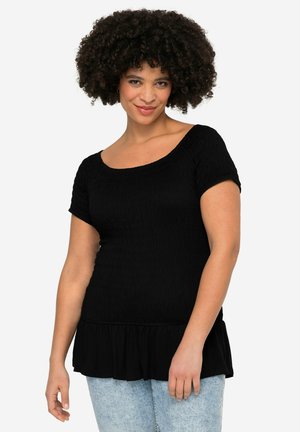Černý peplum top vyrobený z texturované tkaniny, s krátkými rukávy a širokým výstřihem, s volánovým lemem. V kombinaci se světlemodrými džíny.