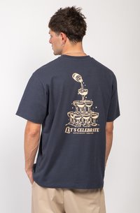 Navyblauw katoenen t-shirt met een grafisch ontwerp van gestapelde glazen en de tekst "Laten we vieren" in beige op de rug gedrukt.