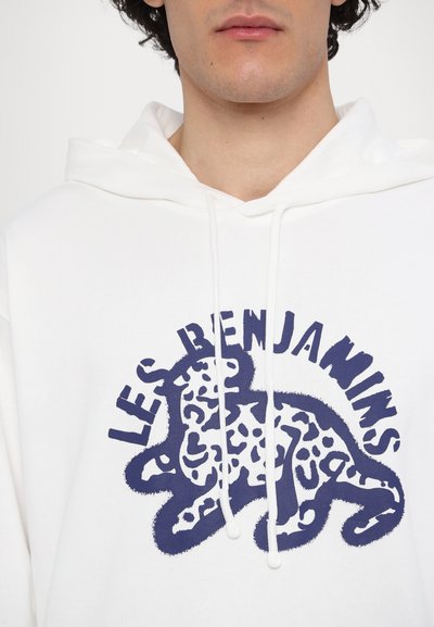 Hoodie blanc avec un graphique de léopard bleu et le texte "LES BENJAMINS." Possède des cordons de serrage et une coupe décontractée. Matière en coton doux.