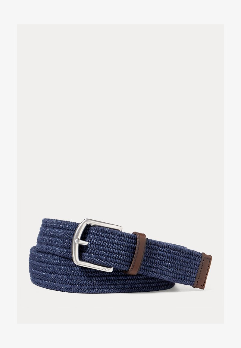 Cintura intrecciata blu navy con fibbia metallica argento e passante e punta in pelle marrone, arrotolata su sfondo bianco semplice.