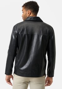 Schwarze Lederjacke mit scharfem Kragen, glatter Textur und Nahtdetails. Bietet eine moderne Passform mit einem mittellangen Schnitt.