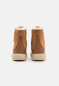 Stivaletti alla caviglia in suede marrone con fodera in pelliccia, chiusura con zip laterali e suola in gomma beige. Presentano un logo impresso sul retro.