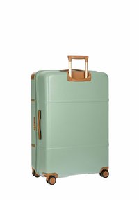 Maleta rígida en verde menta con acentos en marrón. Cuenta con un asa retráctil, cuatro ruedas y una superficie texturizada.