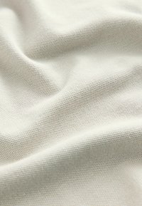 Licht beige stof met een zachte, gestructureerde, gebreide oppervlakte, met subtiele rekken en plooien.