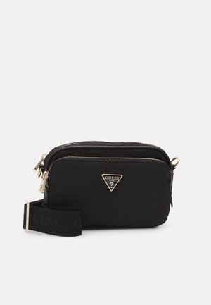 Sac bandoulière noir Guess avec fermetures éclair dorées, logo triangulaire, poche avant et sangle en tissu réglable sur fond blanc.