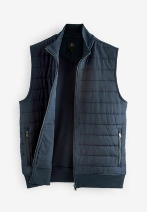 Marineblauwe gewatteerde vest met hoge kraag, ritssluiting aan de voorkant en zijzakken. Ribgebreide zoom en subtiele gewatteerde textuur. Lichtgewicht stof.
