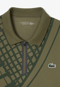 Slim fit polo shirt in olijfgroen met een groen ruitpatroon. Kenmerkt zich door een ritssluiting bij de kraag en een klein geborduurd krokodillenlogo.