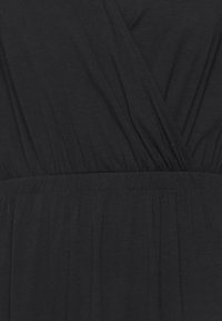 Czarna sukienka o kroju kopertowym, z marszczoną talią i miękkim, teksturowanym materiałem. Tkanina wydaje się lekka i zwiewna.