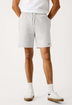 Pantalones cortos de sudadera de algodón gris con cintura elástica, cordón ajustable y bolsillos laterales. Presentan un pequeño logotipo en el dobladillo y un corte relajado.