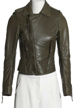 Chaqueta de cuero verde oliva oscuro recortada con cremallera frontal asimétrica y bolsillos con cremallera combinada con pantalones blancos de tiro alto.