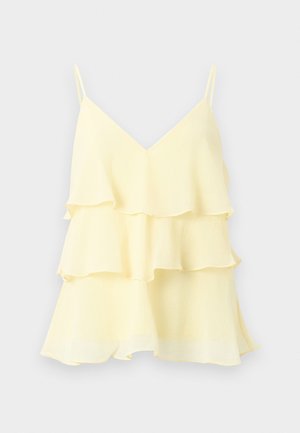 Ανοιχτό κίτρινο αμάνικο τοπ με V-λαιμόκοψη, με τρεις στρωματοποιημένες βολάν και λεπτές ράντες σε μονόχρωμο φόντο.