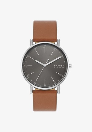 Skagen Armbanduhr mit grauem Zifferblatt, silbernen Zeigern, weißen Minutenmarkierungen und braunem Lederarmband, die 9:10:35 anzeigt.