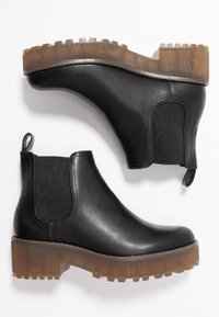 Botas de piel negra hasta el tobillo con un acabado mate, paneles laterales elásticos y una suela de goma gruesa y translúcida para mejorar la tracción.