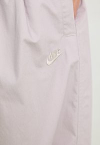 Lyse lavendel Nike shorts med tekstureret overflade, med et subtilt broderet logo på siden og en afslappet silhuet.