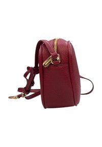 Borsa a tracolla in pelle rossa con forma arrotondata, hardware della cerniera in oro e tracolla regolabile. Presenta una superficie testurizzata per un tocco di dettaglio in più.